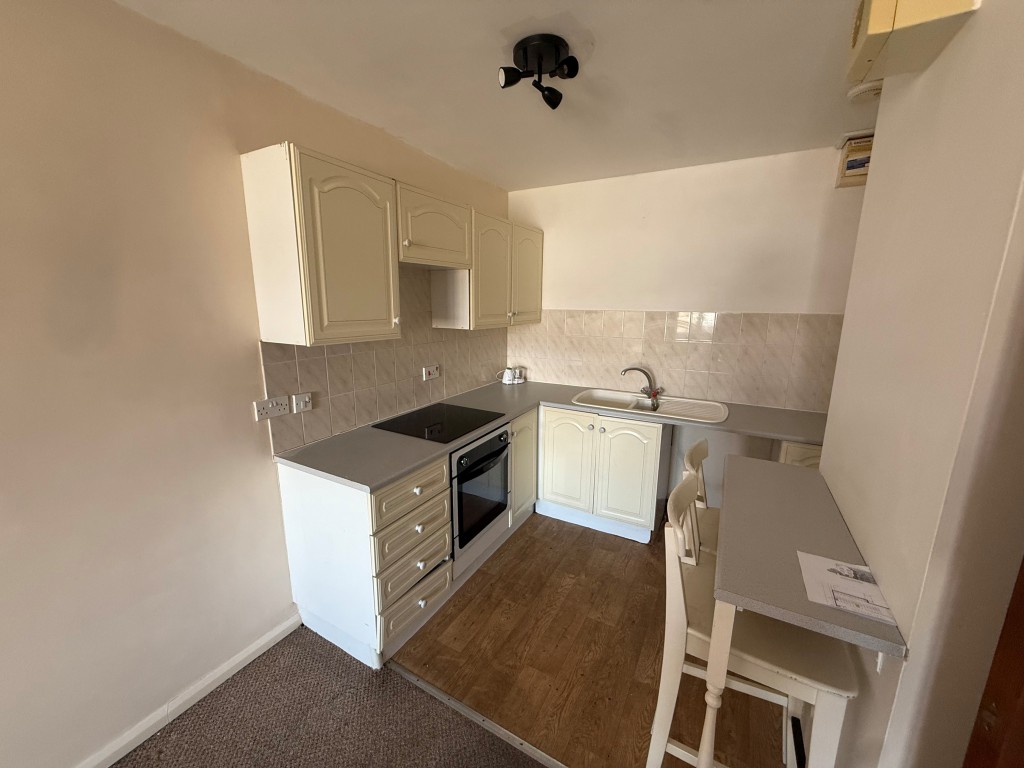 Lot: 219 - ONE-BEDROOM FLAT IN NEED OF MODERNISATION - Kitchen with fitted cabinets and seating area